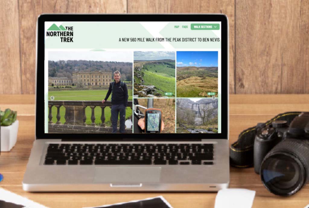 A desk with a laptop and camera on it showing the northern spine website