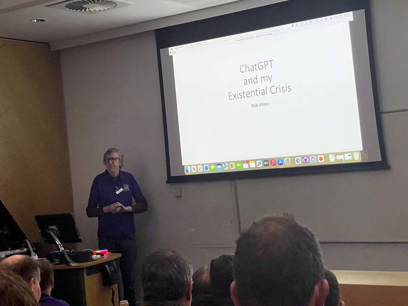 Rob Miles giving a talk in front of a large projector screen