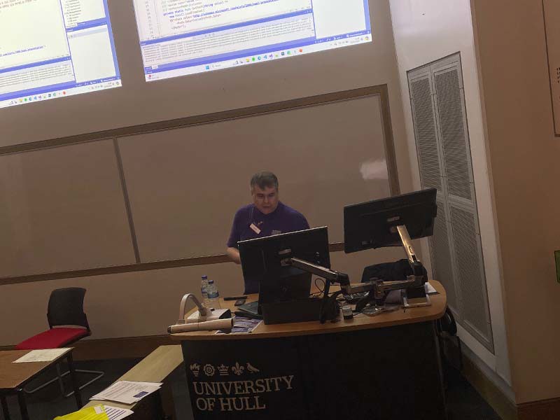 Peter Bull in giving a talk in front of two projection screens